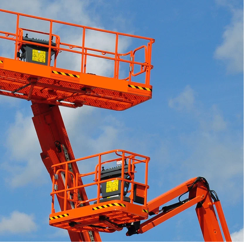 Two boom lift baskets, in the air, with the blue sky behind them.
